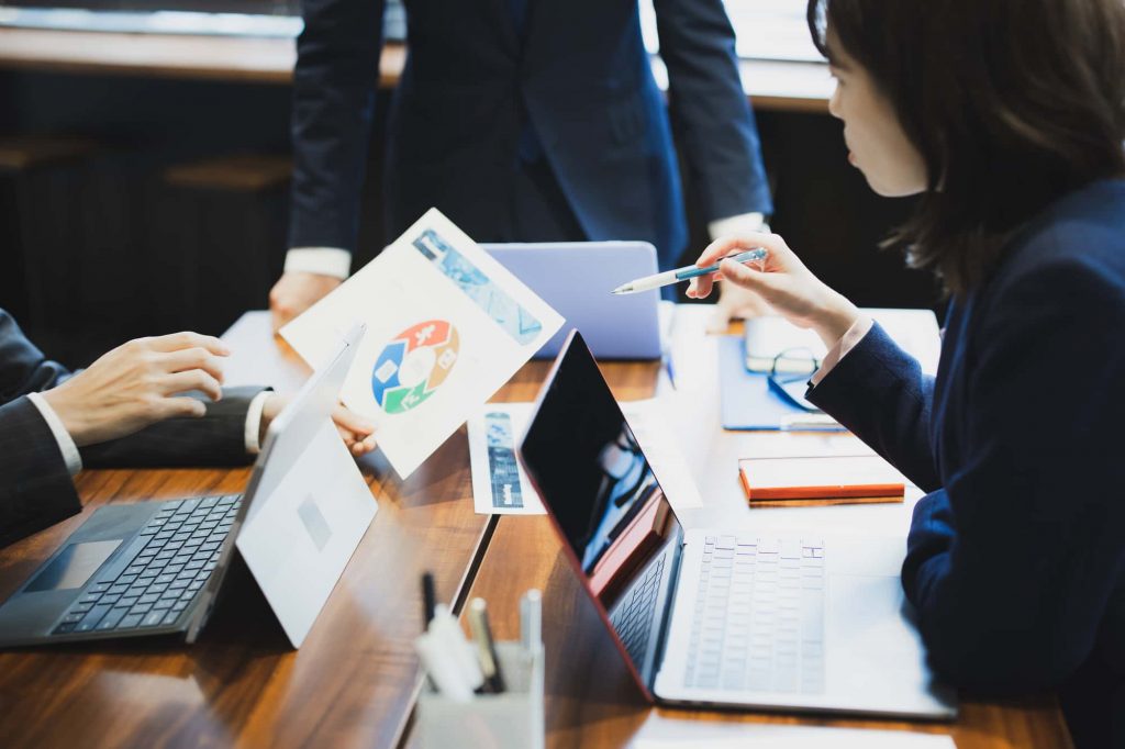 パソコンと資料を見ながら会議するビジネスパーソン