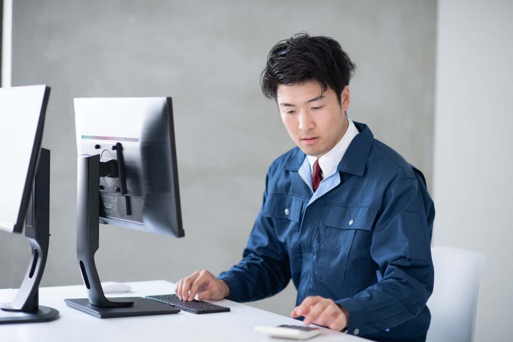 パソコンと電卓で作業をするビジネスパーソン