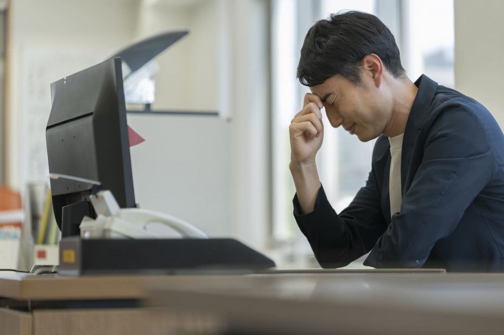 パソコンを見ながら悩むビジネスパーソン