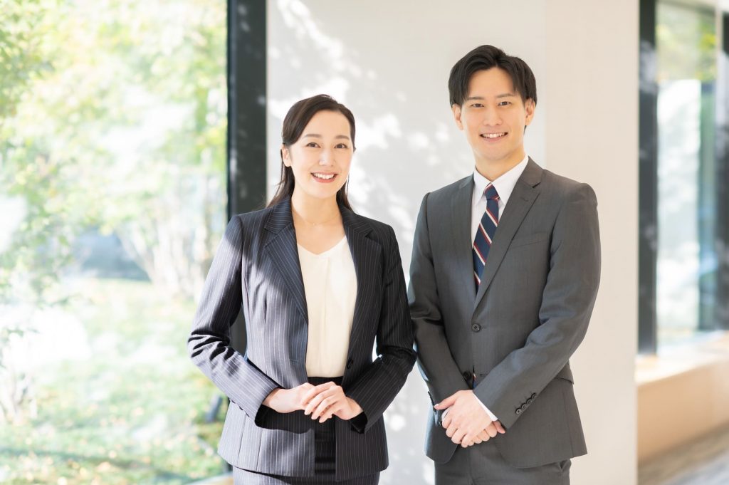 笑顔で立つ2人のビジネスパーソン