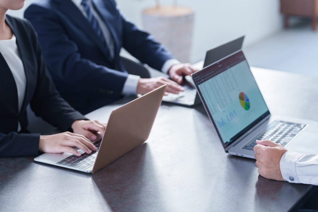 パソコンを開きながらミーティングする3人のビジネスパーソン