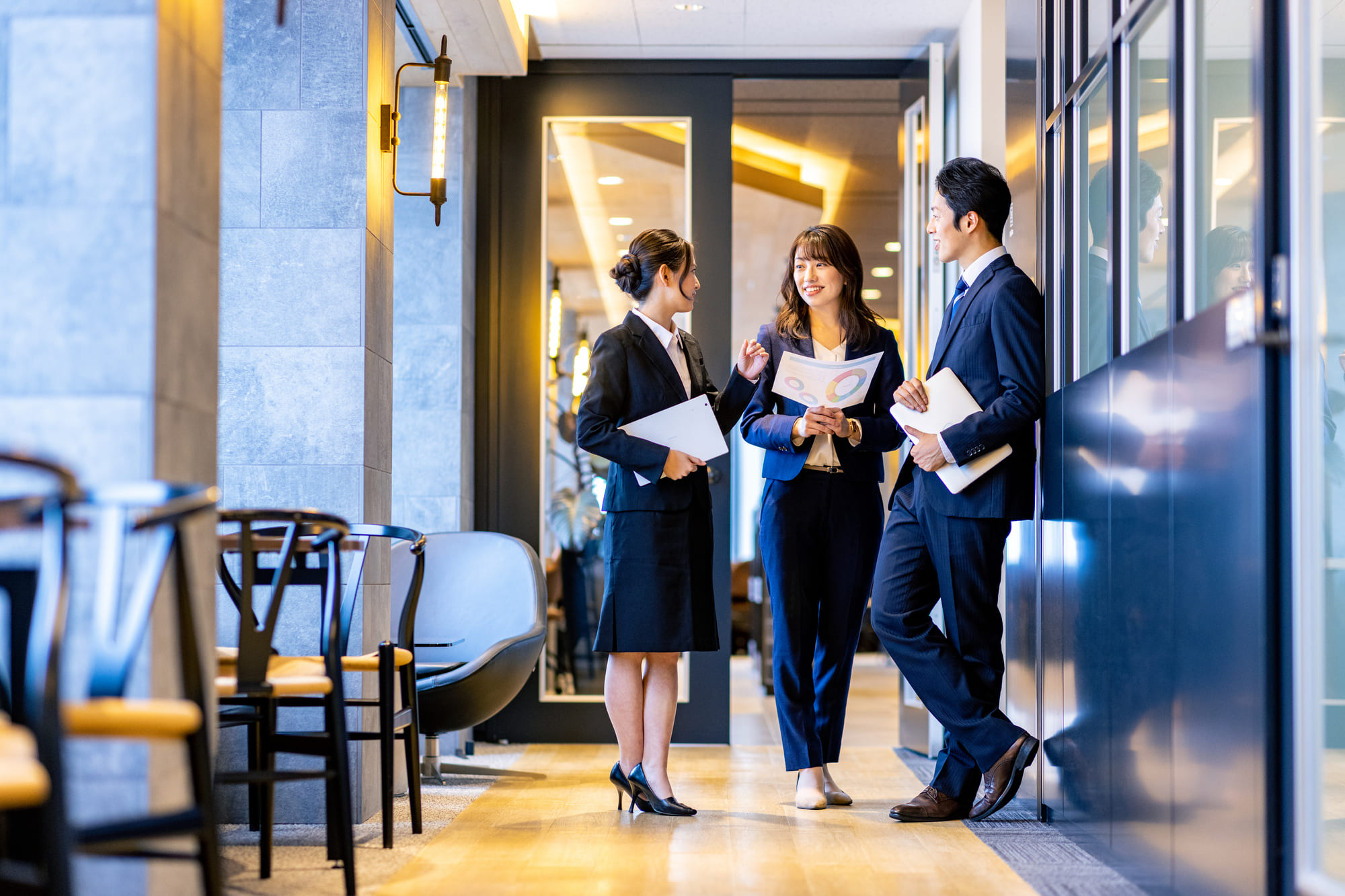 オフィスで立ち話をする3人のビジネスパーソン