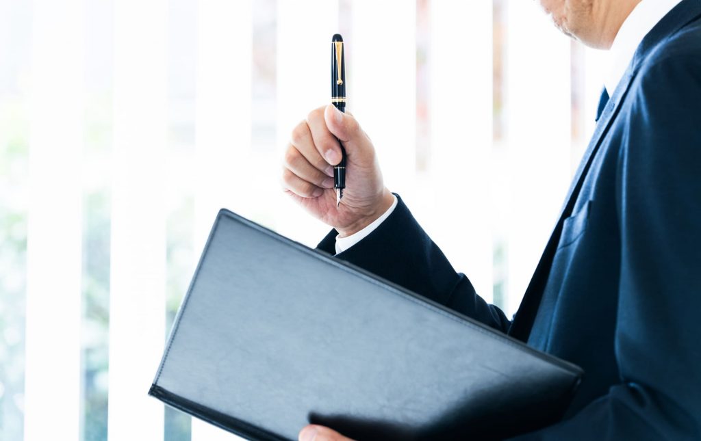 資料とペンを持ったビジネスパーソン