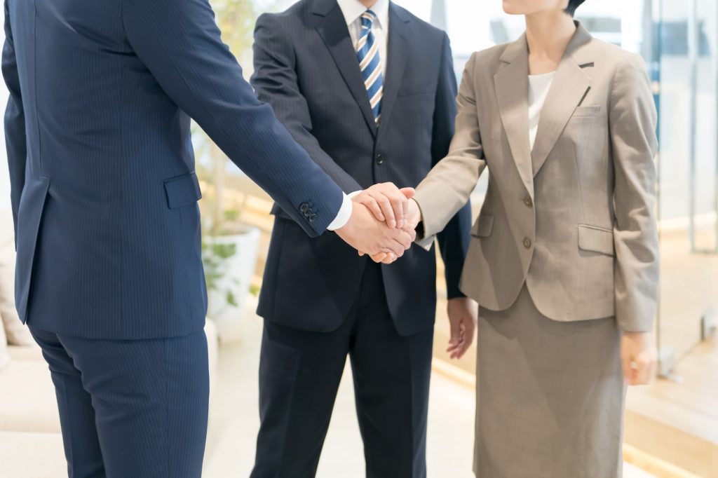 握手をする3人のビジネスパーソン
