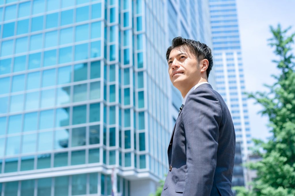 オフィスビルの前に立つビジネスパーソン