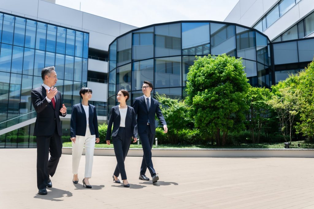 4人のビジネスパーソンがオフィスの前を歩く様子
