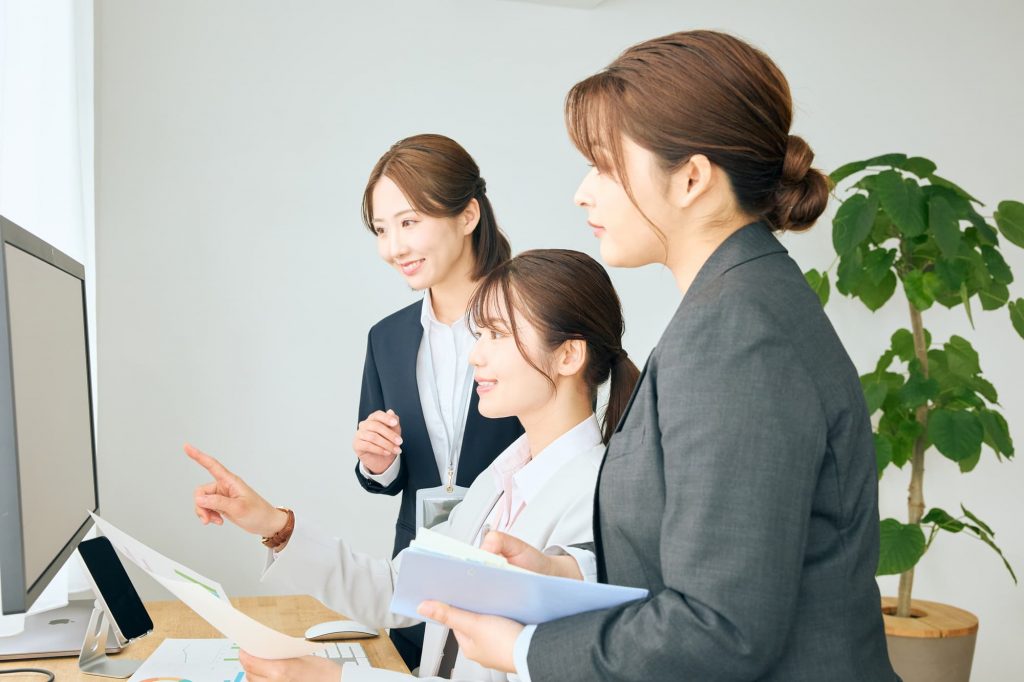 パソコン画面を見ながら打ち合わせする3人のビジネスパーソン