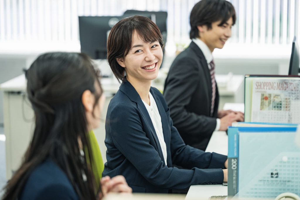 オフィスで笑顔で会話する3人のビジネスパーソン