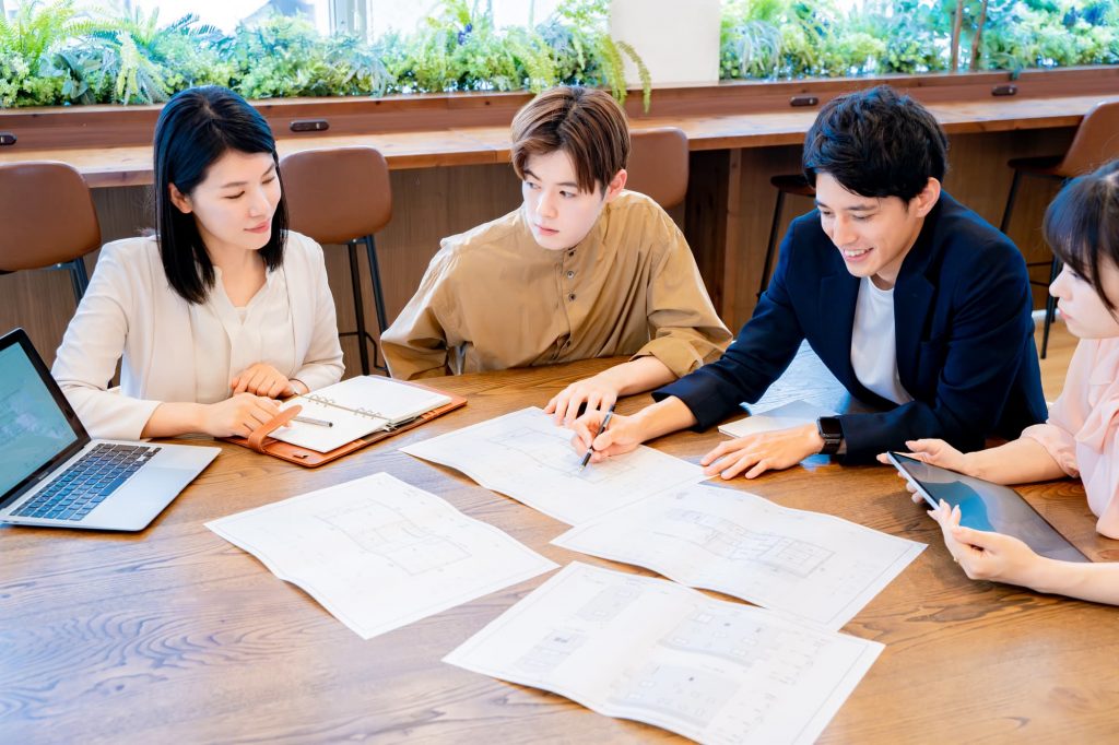 資料を広げながら打ち合わせする4人のビジネスパーソン