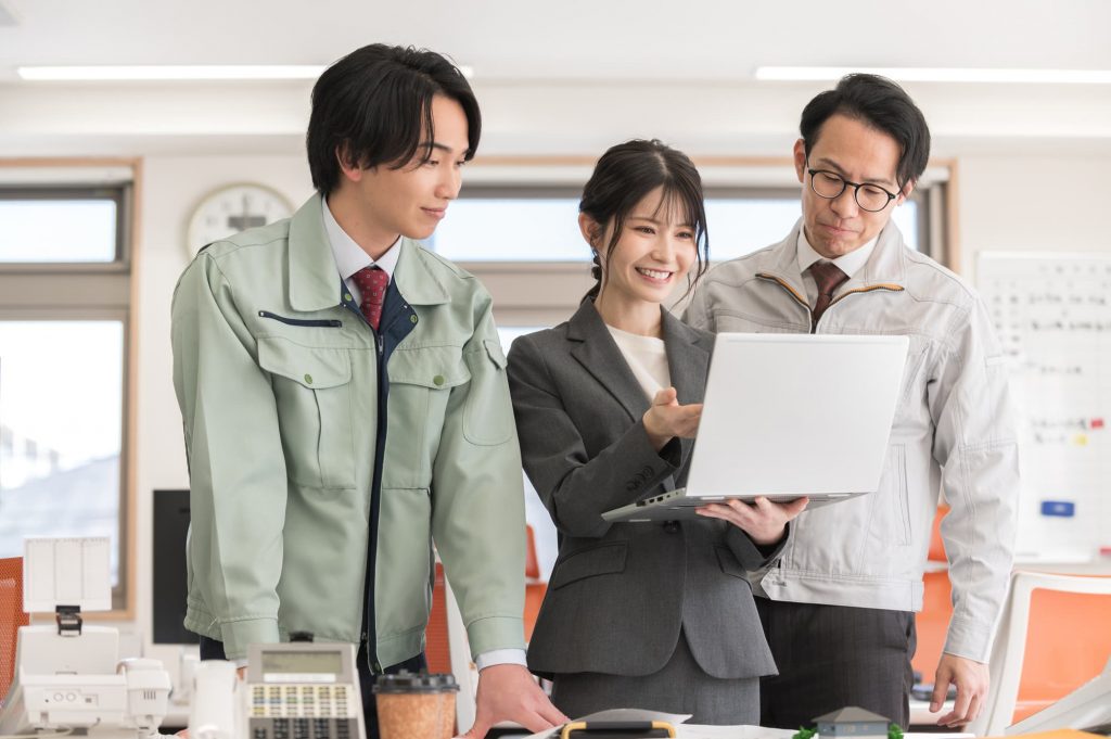 パソコンを見ながら話す3人のビジネスパーソン