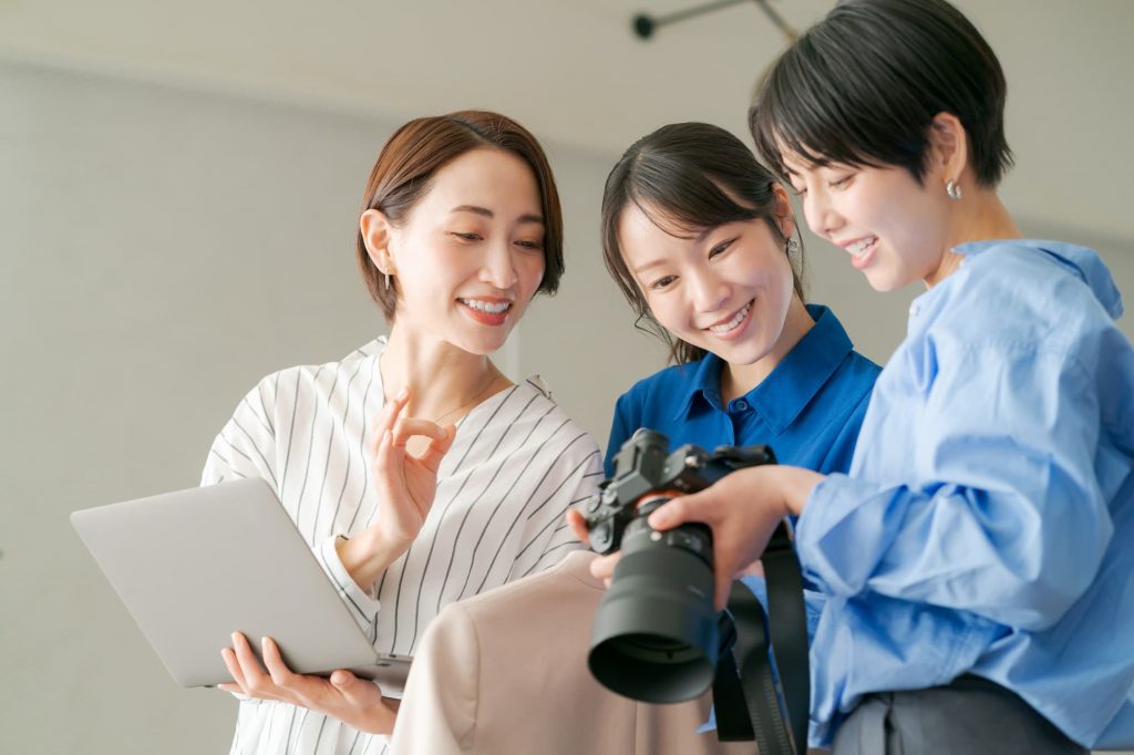 カメラで撮影した画像を見ながら話す3人のビジネスパーソン