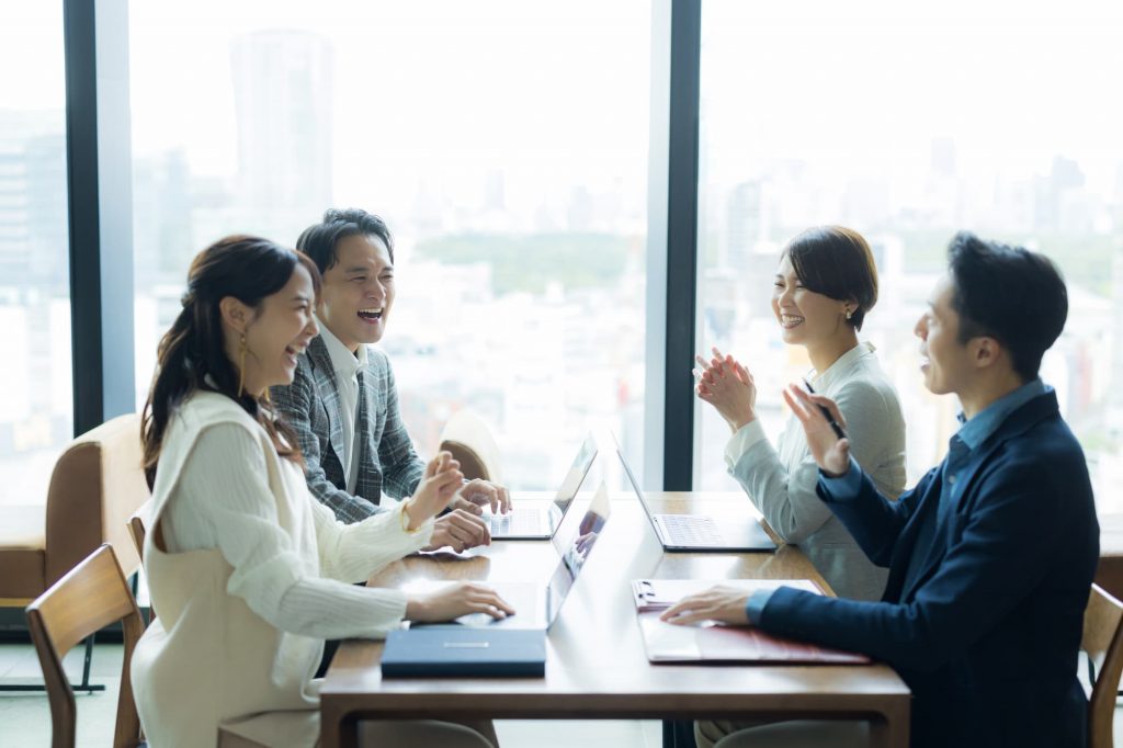 笑顔で打ち合わせをする4人のビジネスパーソン