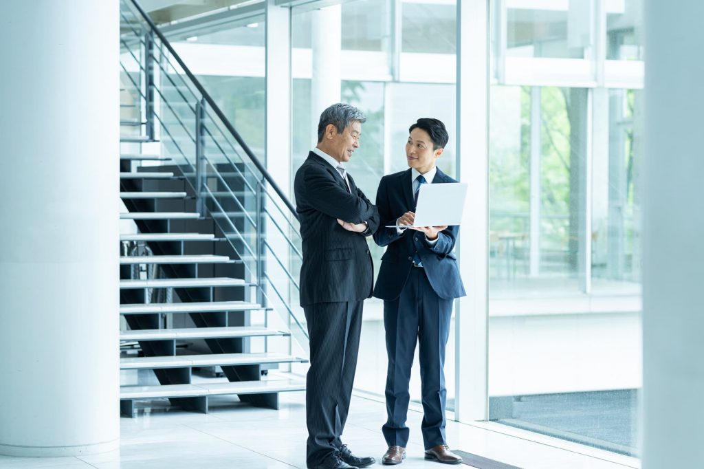 オフィスで立ち話をする2人のビジネスパーソン

