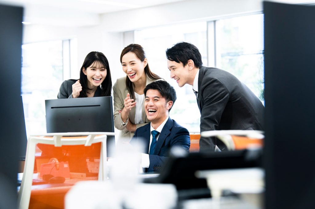 パソコンを見ながら喜ぶ4人のビジネスパーソン
