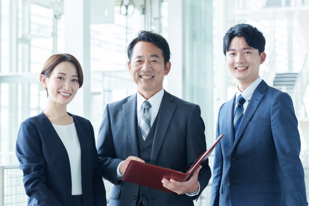 笑顔で立つ3人のビジネスパーソン