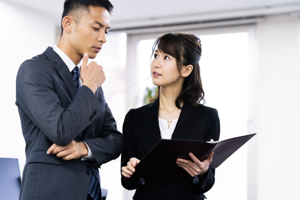 資料を見ながら話す2人のビジネスパーソン
