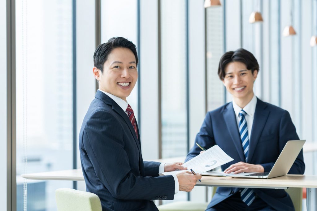 笑顔でデスクに座る2人のビジネスパーソン
