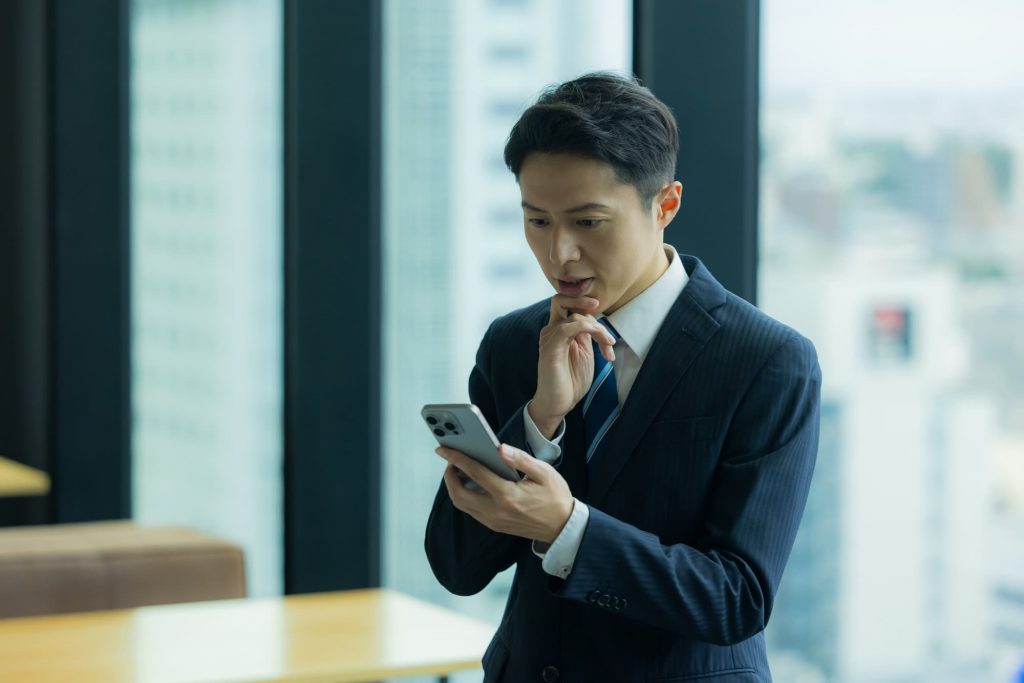電話を見ながら考えるビジネスパーソン