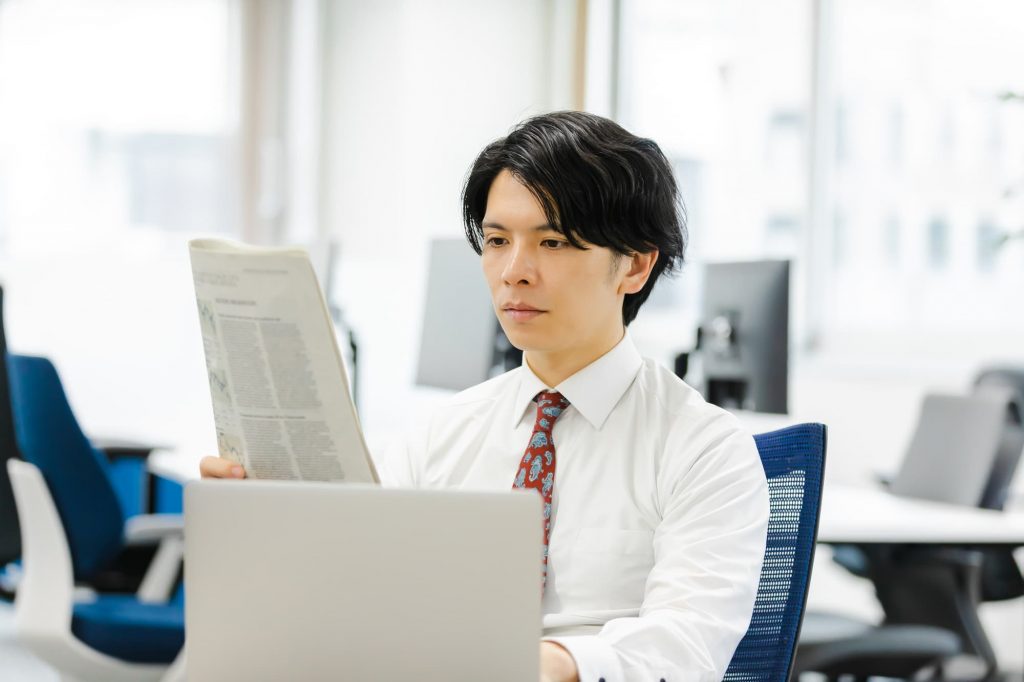 デスクで新聞を読むビジネスパーソン
