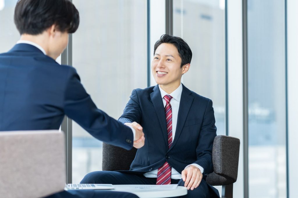オフィスで握手をする2人のビジネスパーソン