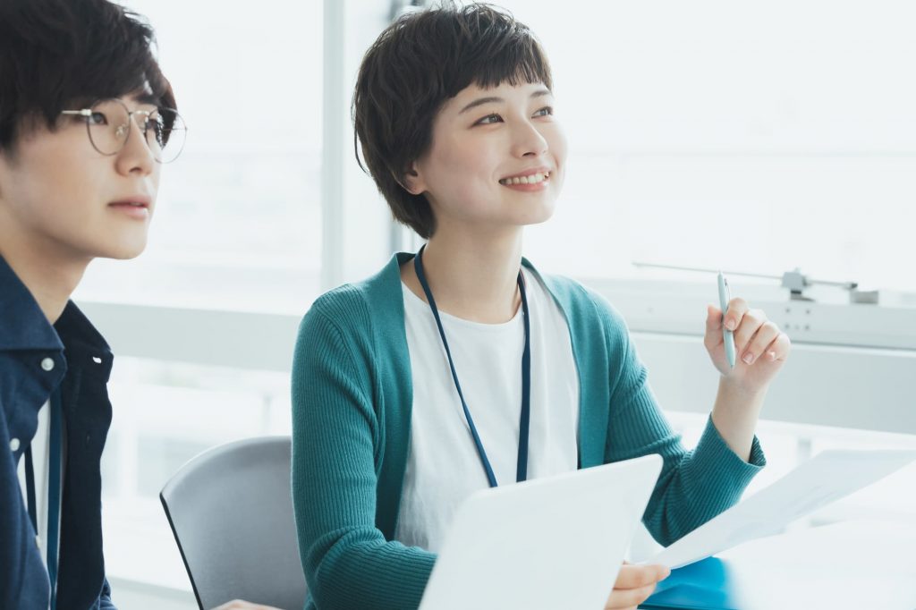 資料を見ながら話す2人のビジネスパーソン
