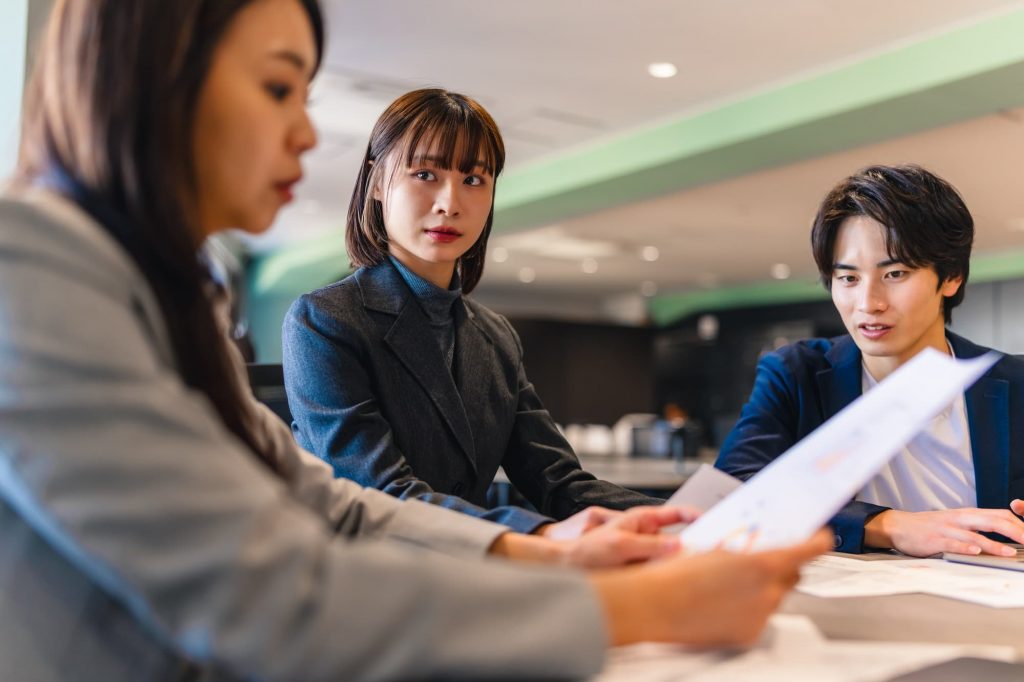 書類を確認しながら打ち合わせする3人のビジネスパーソン