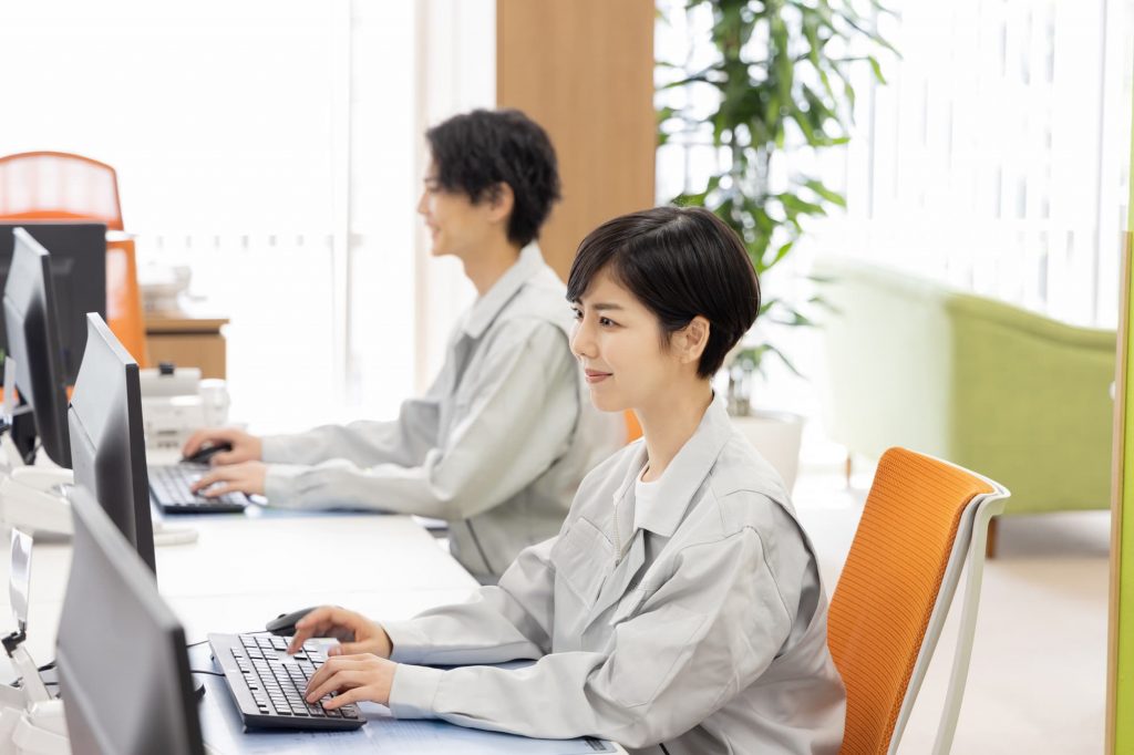 パソコン作業をする作業服を着た2人のビジネスパーソン