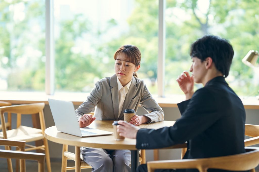 カフェスペースで打ち合わせをする2人のビジネスパーソン