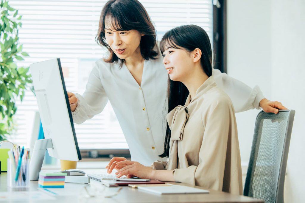 パソコンを見ながら話をする2人のビジネスパーソン