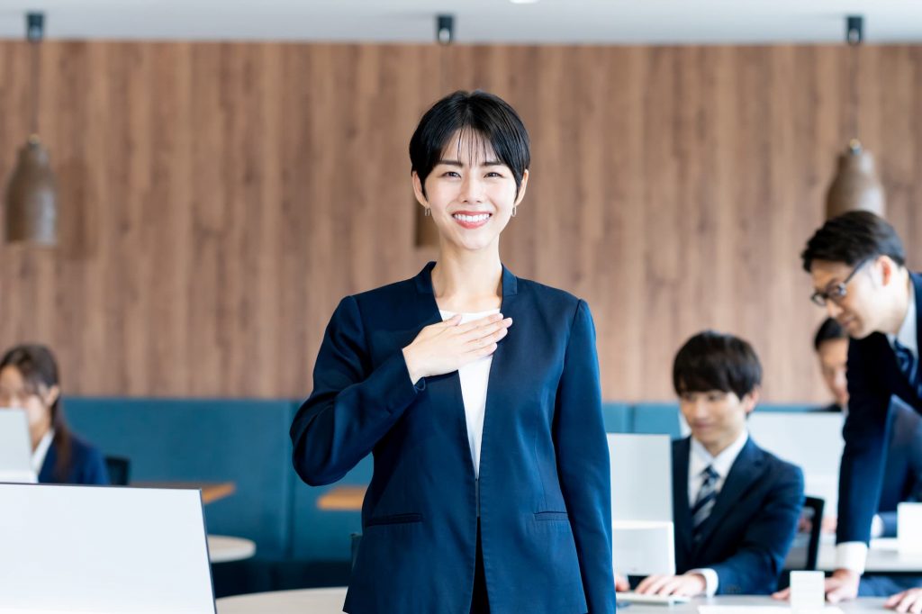 笑顔で手を胸に置くビジネスパーソン