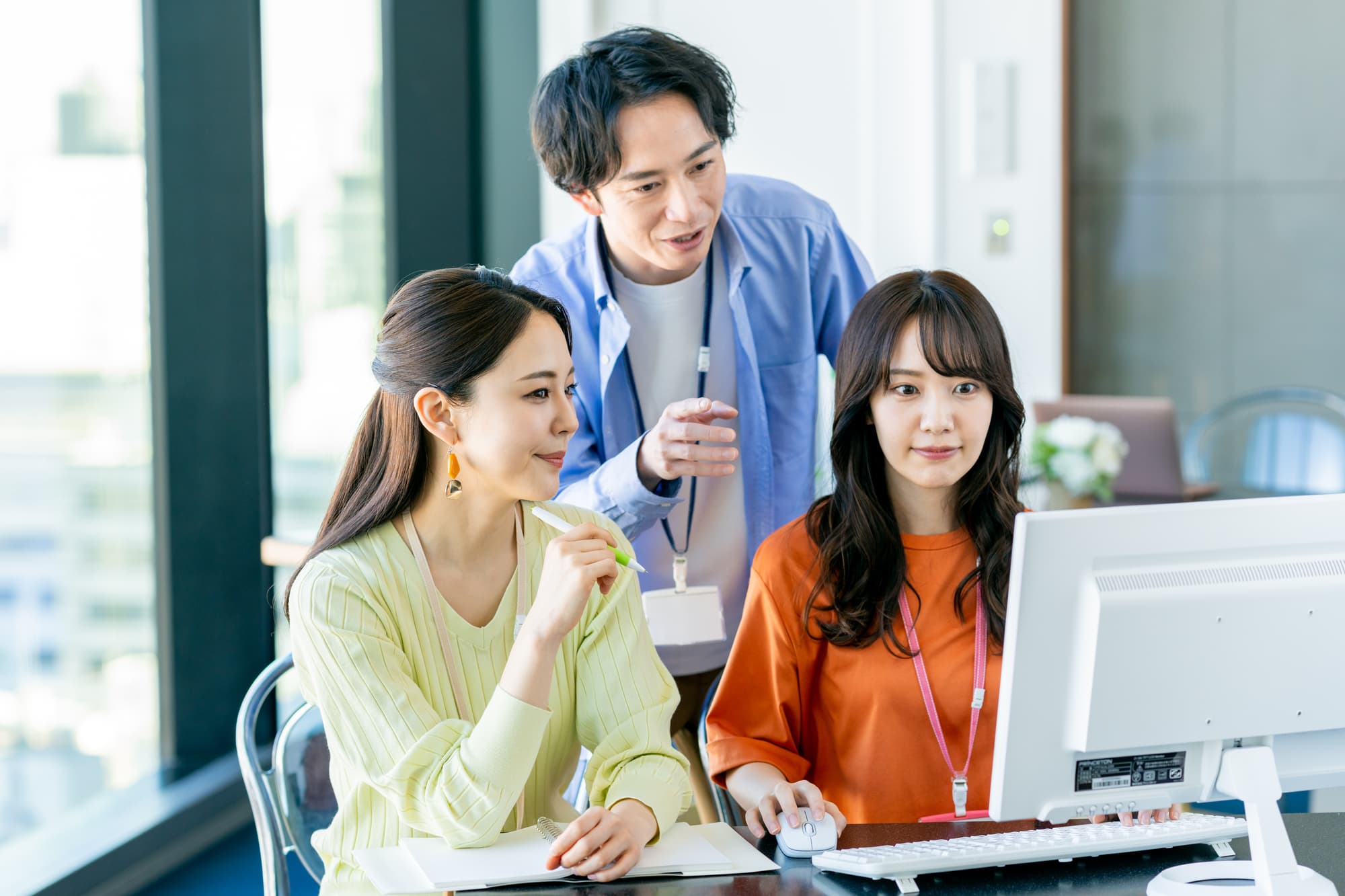 パソコンを見ながら話す3人のビジネスパーソン