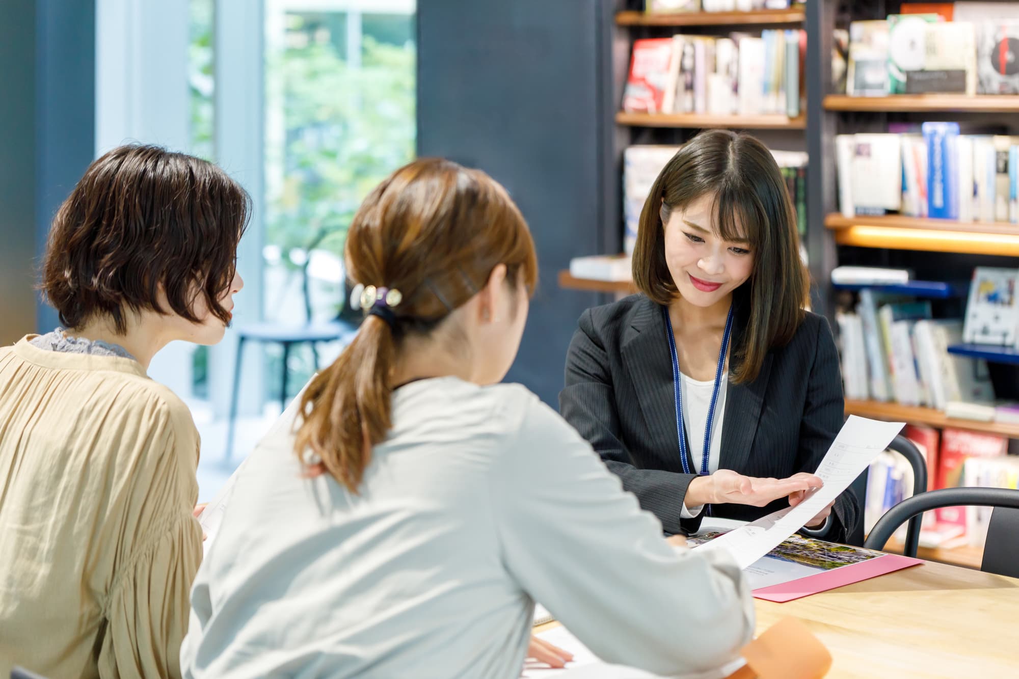 パソコンとタブレットを見ながら打ち合わせする3人のビジネスパーソン